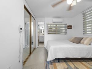 Un dormitorio blanco con una cama y un espejo. en Tropical Naguabo Beach House Pool n Beach, en Naguabo