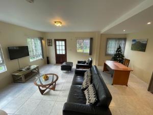 a living room with a black leather couch and a piano at Christiana Apartment Morne Daniel in Canefield