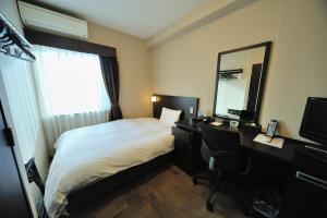 a hotel room with a bed and a desk and a mirror at Dormy Inn Express Koriyama in Koriyama +37 photos