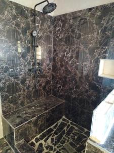 een badkamer met een douche en een zwarte marmeren muur bij Silver Fish Resort Villa in Magila