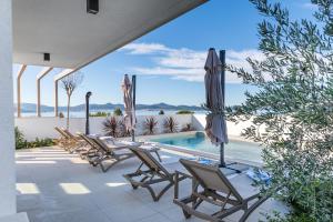 a patio with chairs and a pool and an umbrella at Villa Mare Zadar in Zadar