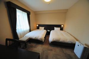 a bedroom with two beds and a table and a window at Dormy Inn Express Koriyama in Koriyama