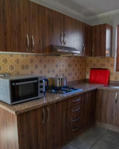 una cocina con armarios de madera y microondas en una encimera en Elegant Family Chalet a Imi Ouaddar Comfort & Calm, en Agadir
