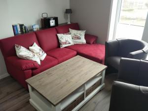 een woonkamer met een rode bank en een salontafel bij Ferienwohnung Harlezauber Carolinensiel in Carolinensiel