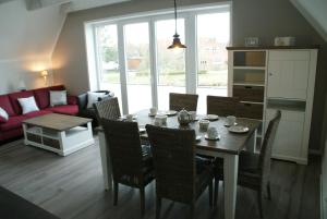 een woonkamer met een tafel, stoelen en een bank bij Ferienwohnung Harlezauber Carolinensiel in Carolinensiel
