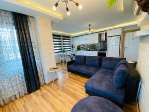 ein Wohnzimmer mit einer blauen Couch und einer Küche in der Unterkunft Royal Loft Suit in Antalya