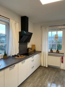 ヴィンターベルクにあるDottie's Placeの白いキャビネットと窓付きの広いキッチン