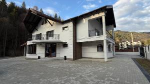 Casa blanca grande con balcón en la entrada en Pensiunea Seraris, en Voineasa