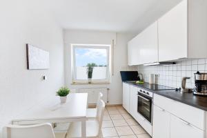 eine weiße Küche mit einem Tisch und einem Fenster in der Unterkunft Schöne Wohnung in Geseke in Niederdorla