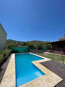 een blauw zwembad met een houten terras bij Cabañas El Pela in Villa Carlos Paz