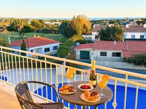 un tavolo con bicchieri di vino e cibo su un balcone di Balaia Poolside House with Sea View by BeCherish a Branqueira