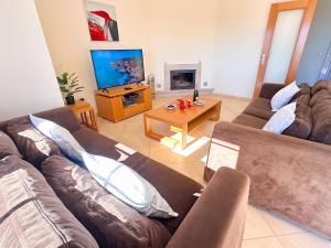 un soggiorno con due divani e una televisione di Balaia Poolside House with Sea View by BeCherish a Branqueira