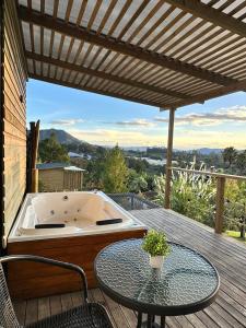 Alto Paraiso Glamping "A" في Carmen de Viboral: حوض جاكوزي على سطح مع طاولة