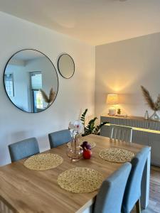 Łeba Garden Apartament في ليبا: طاولة غرفة الطعام مع كراسي زرقاء ومرآة