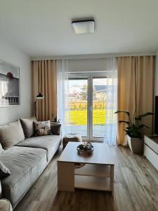 Łeba Garden Apartament في ليبا: غرفة معيشة بها أريكة وطاولة +11 صورة