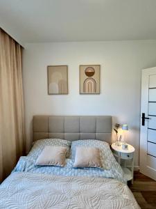 a bedroom with a bed with two pillows and a table at Łeba Garden Apartament in Łeba