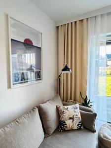 Łeba Garden Apartament في ليبا: غرفة معيشة مع أريكة ونافذة
