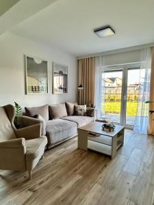 Łeba Garden Apartament في ليبا: غرفة معيشة مع أريكة وطاولة قهوة