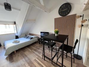 Studio cosy tout confort proche Cathédrale dans rue calme في أورليان: غرفة نوم بسرير ومكتب وساعة