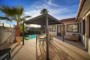 a patio with a table and chairs under an umbrella at FRGK Villa Contemporaine Studio Indépendant Piscine, Calme Vue Dégagée in Le Cannet
