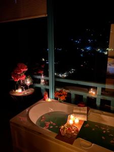 un baño con bañera con velas y una ventana en The Elevia, Jibhi, en Jibhi