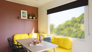 a dining room with a table and yellow chairs at Camping Tikayan Saint Clair - Maeva in Moustiers-Sainte-Marie