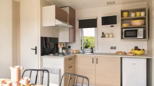 a kitchen with white cabinets and a table and chairs at Camping Tikayan Saint Clair - Maeva in Moustiers-Sainte-Marie +12 photos