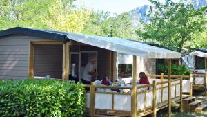 a man standing in front of a house with a tent at Camping Tikayan Saint Clair - Maeva in Moustiers-Sainte-Marie