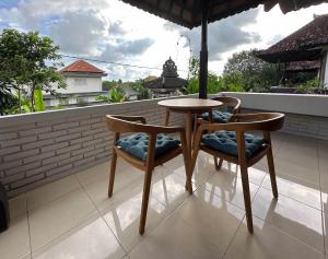 Una mesa de madera y dos sillas en un balcón. en Why Not Villas, en Ubud