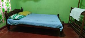 Cama en habitación con pared verde en Sinharaja Tour Guide, en Nikawatawana 13 fotos más