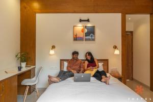 two people sitting on a bed with a laptop at Zostel Pune (Viman Nagar) in Pune +51 photos