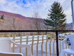 uma varanda com duas cadeiras brancas e uma árvore em Comfort Studio - Design Moderno & Free Parking em Chiusa di Pesio