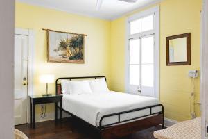 a bedroom with yellow walls and a bed with a table at Curry House - Rooms 3 & 4 in Key West