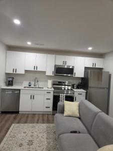 eine Küche mit weißen Schränken und einem grauen Sofa in der Unterkunft The Heavenly Crib in Saskatoon