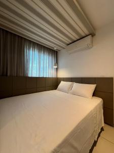 uma grande cama branca em um quarto com janela em Flat Beach Class Excelsior - Apto Completo para 4 pessoas vista rio e mar em Recife