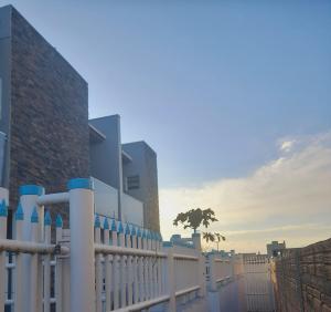 a white fence with a tree in front of a building at Sobrados pertinho do mar in Tramandaí