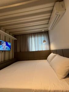 um quarto com uma cama e uma TV na parede em Flat Beach Class Excelsior - Apto Completo para 4 pessoas vista rio e mar em Recife