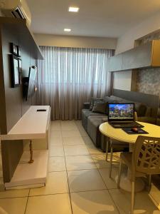uma sala de estar com um sofá e um computador portátil sobre uma mesa em Flat Beach Class Excelsior - Apto Completo para 4 pessoas vista rio e mar em Recife mais 76 fotografias