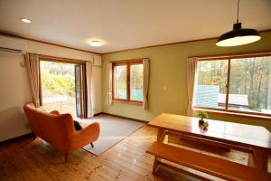a living room with a table and a chair and windows at THE KOYA Nagano in Nagano