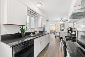 een keuken met witte kasten en zwarte aanrechtbladen bij Pool & Fire Pits • Pet Friendly • 3 BR Home in Las Vegas