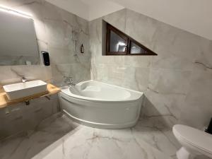 Un baño blanco con bañera y lavabo. en Pensiunea Seraris, en Voineasa