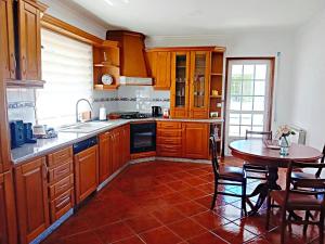 a kitchen with wooden cabinets and a table and a dining room at PESO RIVER HOUSE in Melgaço