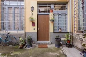 Un edificio con una porta con delle piante in vaso. di Living Bovisa a Milano