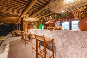 a restaurant with wooden chairs and a bar with windows at Villas Taturé in São Miguel dos Milagres