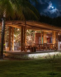 a pavilion with chairs and palm trees at night at Villas Taturé in São Miguel dos Milagres