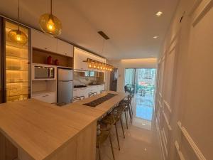 una cocina con una isla larga con una mesa larga en Apto c/ parrilla a 450 m del mar, Perequê SRF0601, en Perequê