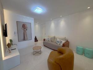 una sala de estar con un sofá y una silla en Apto c/ parrilla a 450 m del mar, Perequê SRF0601, en Perequê