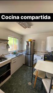 Una cocina con refrigerador de acero inoxidable y una mesa. en Anyrcoy, en Viña del Mar