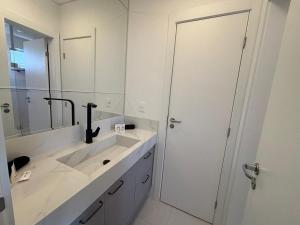 Un baño blanco con lavabo y espejo. en Apto c/ parrilla a 450 m del mar, Perequê SRF0601, en Perequê