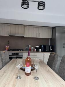 a bottle of wine sitting on a table with two wine glasses at Madona Apartment in Craiova